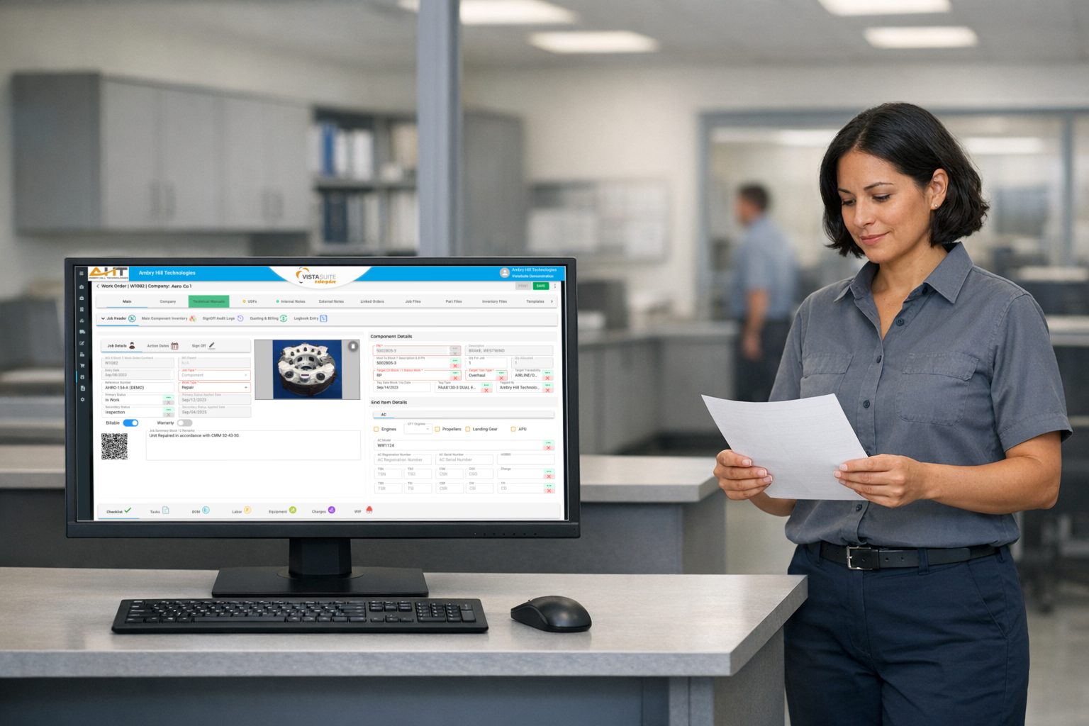 Repair station planner reviewing a document beside a Vista-Suite Enterprise Work Order screen